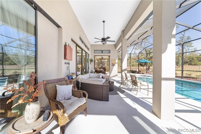 view of patio / terrace featuring an outdoor living space, ceiling fan, and glass enclosure