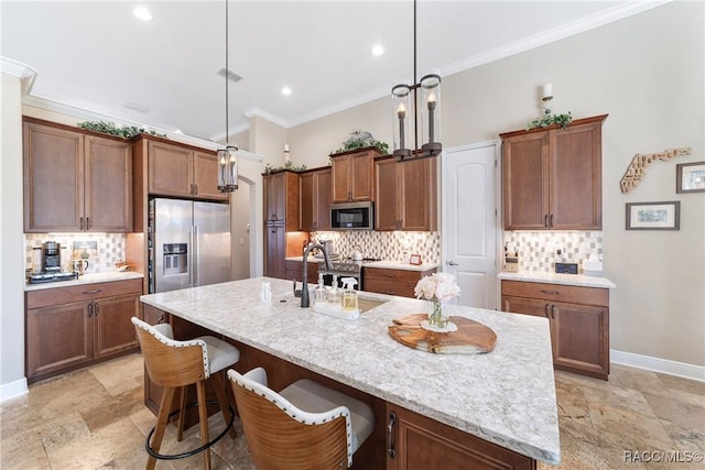 kitchen with hanging light fixtures, backsplash, an island with sink, and appliances with stainless steel finishes