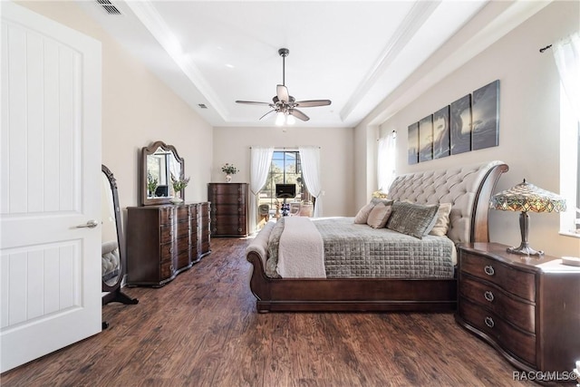 bedroom featuring dark hardwood / wood-style floors, ceiling fan, and a tray ceiling