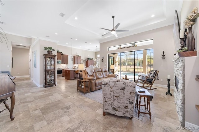 living room featuring a fireplace, a raised ceiling, and ceiling fan