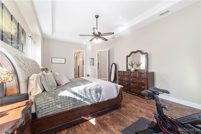 bedroom featuring dark wood-type flooring, ceiling fan, and a tray ceiling