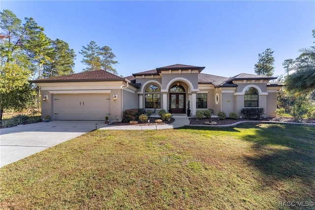 mediterranean / spanish home featuring a garage and a front yard