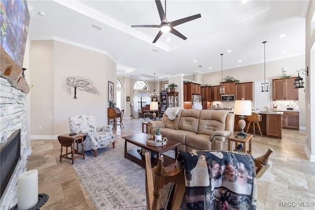 living room featuring a stone fireplace, ornamental molding, and ceiling fan