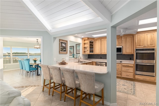 kitchen featuring a breakfast bar area, kitchen peninsula, a water view, and appliances with stainless steel finishes