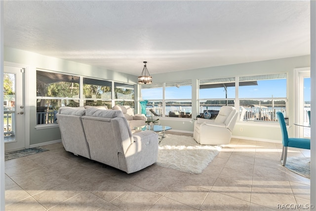 living room with an inviting chandelier, a water view, tile patterned floors, and a wealth of natural light