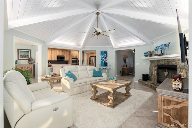 living room featuring ceiling fan, a stone fireplace, lofted ceiling with beams, light tile patterned floors, and wood ceiling