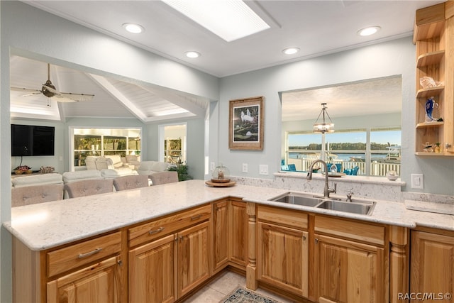 kitchen featuring ceiling fan with notable chandelier, lofted ceiling with beams, light stone counters, and sink