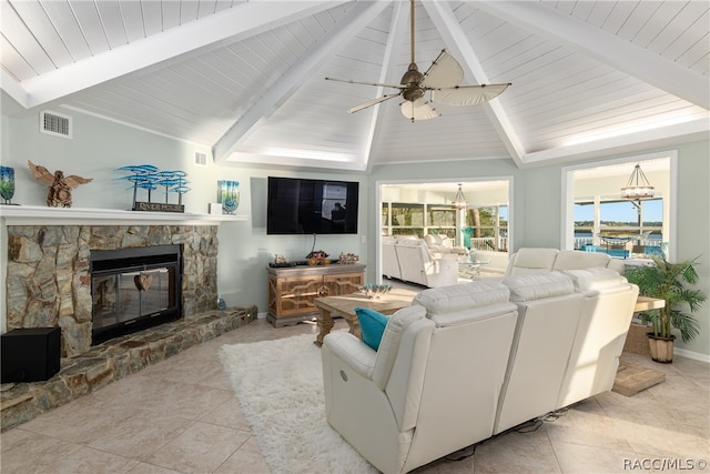 tiled living room with a stone fireplace, ceiling fan, and lofted ceiling with beams