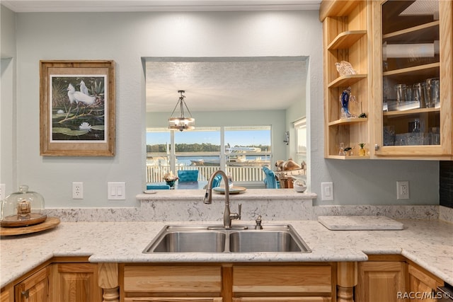 kitchen featuring a chandelier, light stone counters, and sink