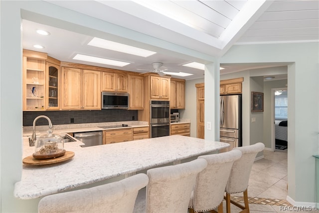 kitchen featuring a breakfast bar, backsplash, sink, kitchen peninsula, and stainless steel appliances