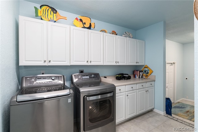 clothes washing area featuring washing machine and clothes dryer, light tile patterned floors, cabinets, and a textured ceiling