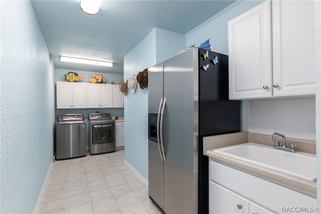 kitchen with washing machine and clothes dryer, sink, stainless steel refrigerator with ice dispenser, a textured ceiling, and white cabinets