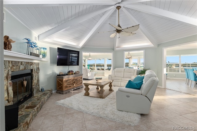 living room featuring ceiling fan, lofted ceiling with beams, light tile patterned flooring, and a fireplace