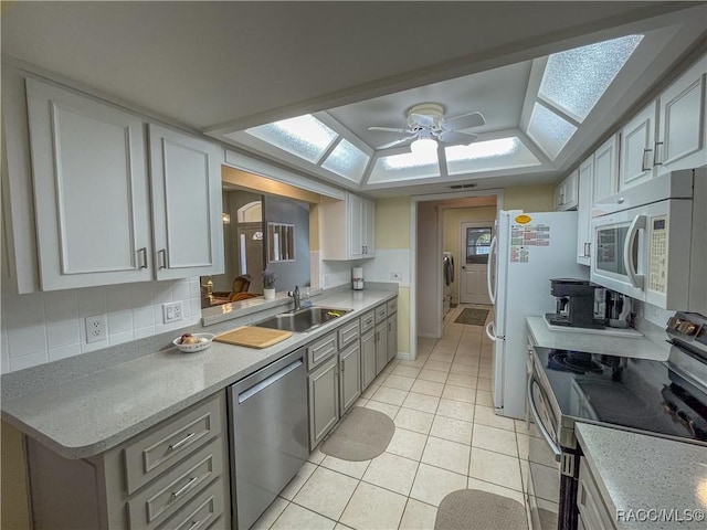 kitchen featuring a skylight, appliances with stainless steel finishes, light countertops, and a sink