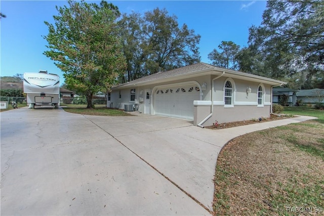 view of home's exterior featuring driveway, an attached garage, central AC, and stucco siding