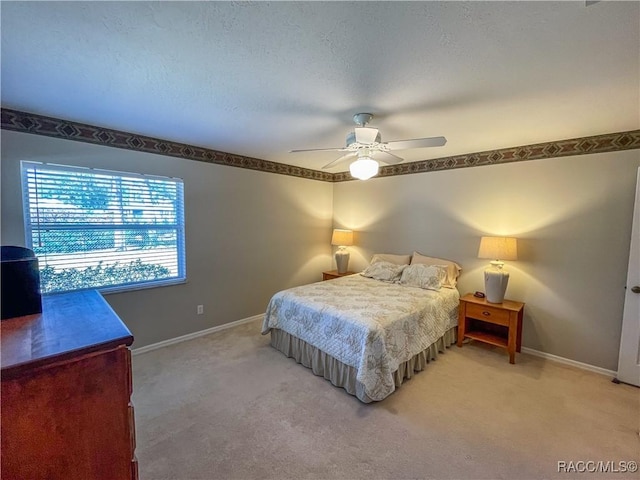 bedroom with baseboards, ceiling fan, a textured ceiling, and light colored carpet