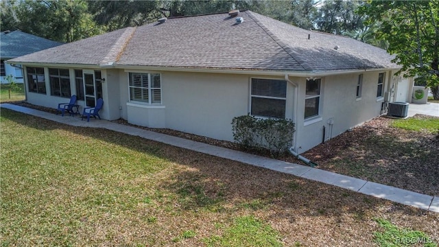 view of property exterior with central air condition unit, roof with shingles, a yard, and stucco siding