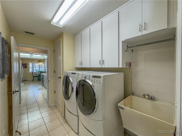 laundry area featuring washing machine and clothes dryer, light tile patterned floors, cabinet space, visible vents, and a sink