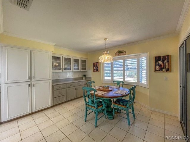 dining area with light tile patterned floors, baseboards, visible vents, and crown molding