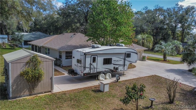 rear view of house featuring an outbuilding, driveway, a lawn, stucco siding, and a storage unit