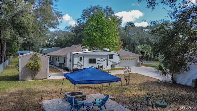 exterior space with an outbuilding, an attached garage, a storage shed, fence, and driveway