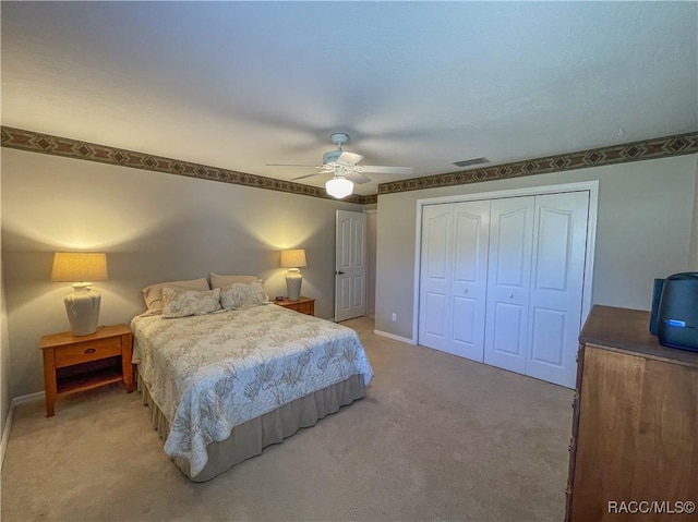 bedroom with a closet, visible vents, a ceiling fan, light carpet, and baseboards