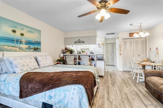 bedroom featuring ceiling fan with notable chandelier and light hardwood / wood-style flooring