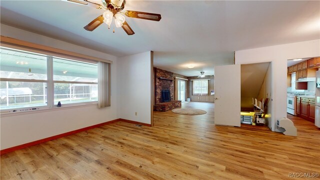 unfurnished living room with a fireplace, ceiling fan, and light hardwood / wood-style flooring