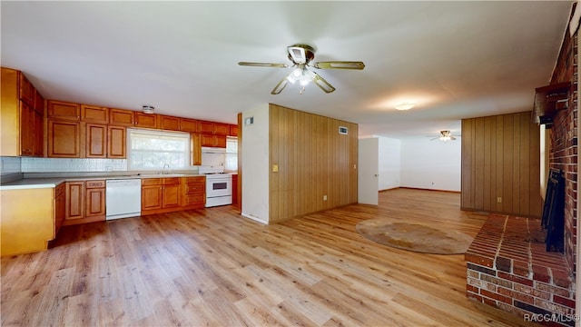 kitchen featuring white appliances, a brick fireplace, ceiling fan, tasteful backsplash, and light hardwood / wood-style floors