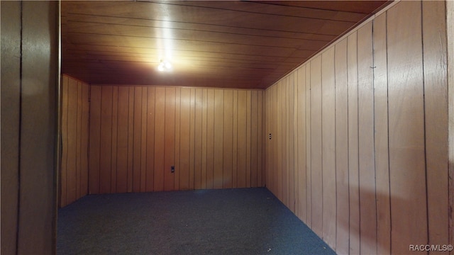 interior space with wooden ceiling, dark carpet, and wooden walls