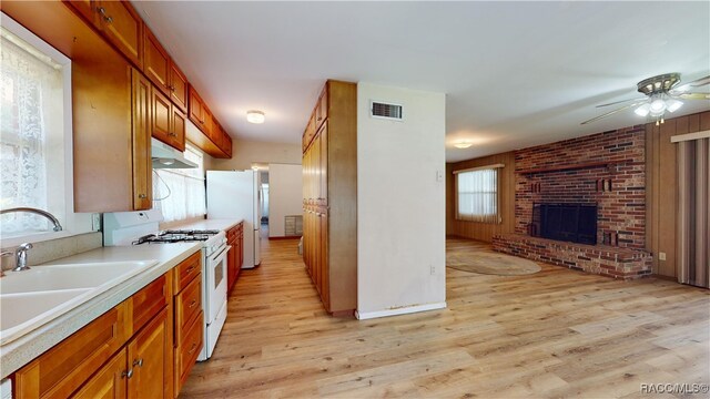 kitchen with ceiling fan, sink, a brick fireplace, light hardwood / wood-style floors, and white appliances