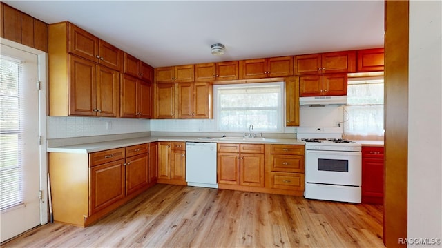 kitchen with light wood-type flooring, decorative backsplash, white appliances, and sink