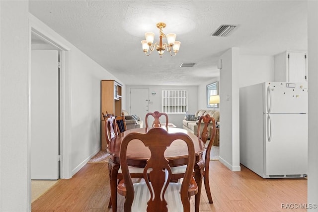 2 James St, Beverly Hills, FL 34465 - dining room featuring light wood finished floors, a chandelier, and a textured ceiling