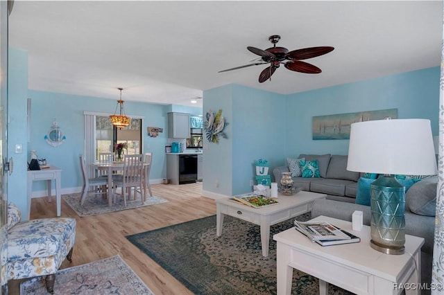 living area with light wood-style floors, baseboards, and a ceiling fan