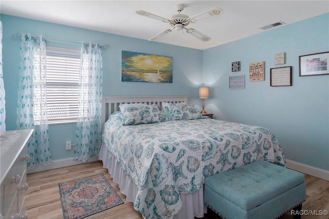bedroom featuring a ceiling fan, light wood-style flooring, visible vents, and baseboards