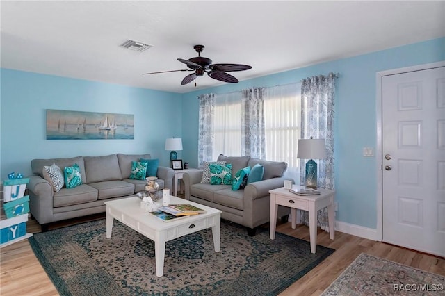 living area featuring visible vents, ceiling fan, baseboards, and wood finished floors