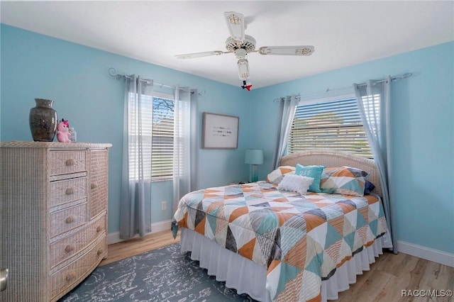 bedroom featuring dark wood-style floors, a ceiling fan, and baseboards