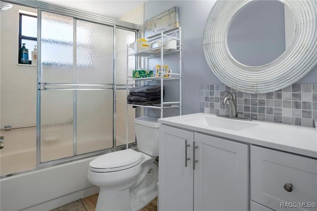 full bathroom featuring decorative backsplash, combined bath / shower with glass door, vanity, and toilet