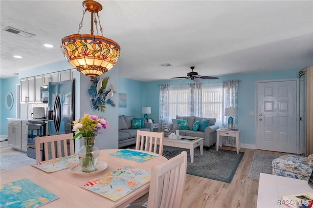 dining space featuring ceiling fan, light wood finished floors, visible vents, and baseboards