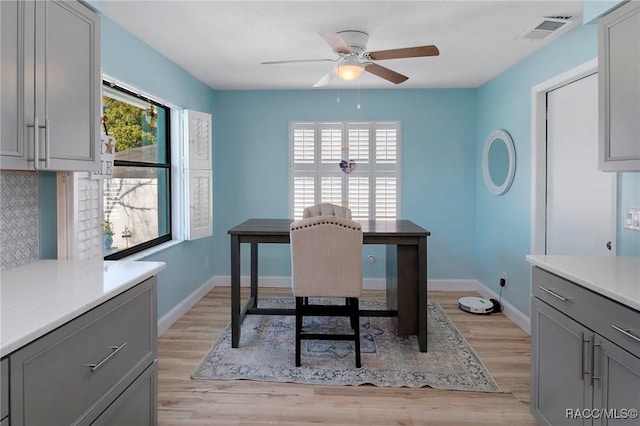 office featuring light wood-type flooring, baseboards, visible vents, and a ceiling fan