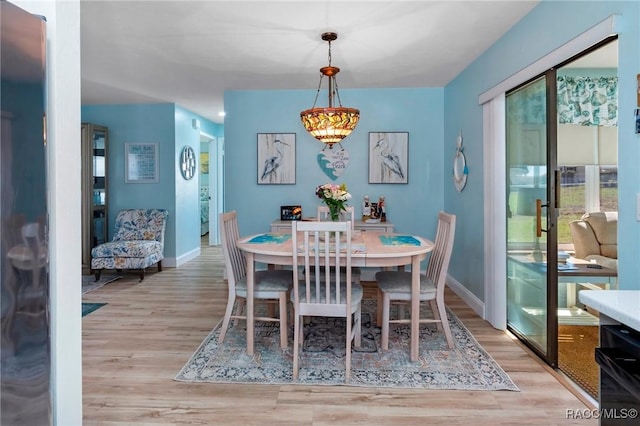 dining space with light wood-type flooring, a healthy amount of sunlight, and baseboards