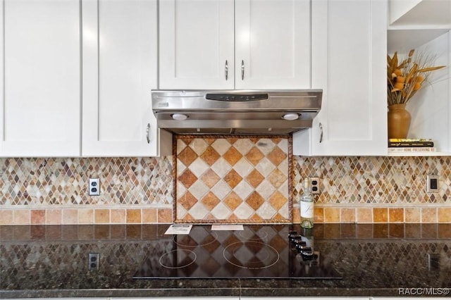 kitchen featuring white cabinets, decorative backsplash, black electric stovetop, and range hood