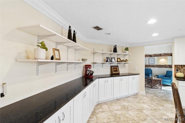 bar featuring white cabinets, dark stone counters, and ornamental molding