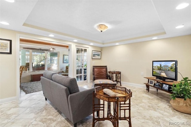 living room featuring a raised ceiling and ceiling fan