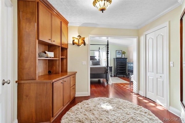 hall featuring lofted ceiling, a textured ceiling, crown molding, and dark wood-type flooring