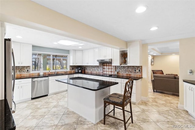 kitchen with white cabinetry, a center island, sink, a kitchen bar, and appliances with stainless steel finishes