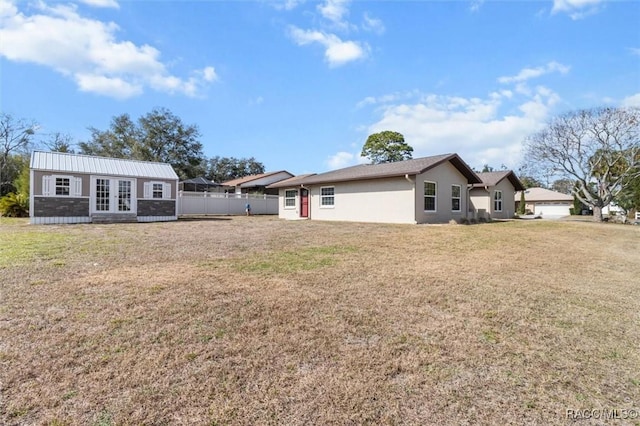 back of house with an outbuilding and a lawn