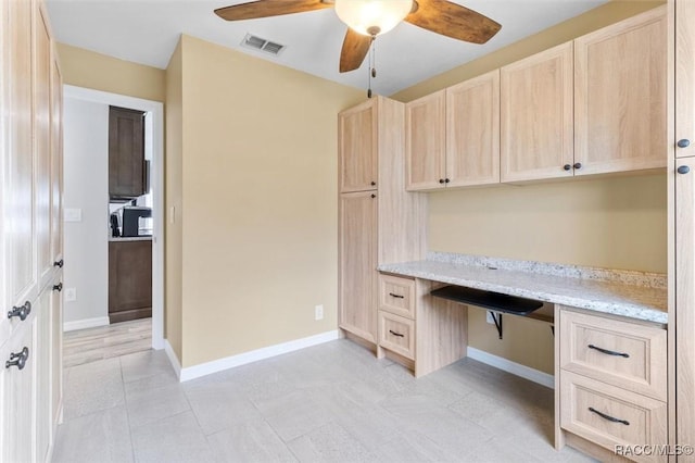 unfurnished office featuring built in desk and ceiling fan