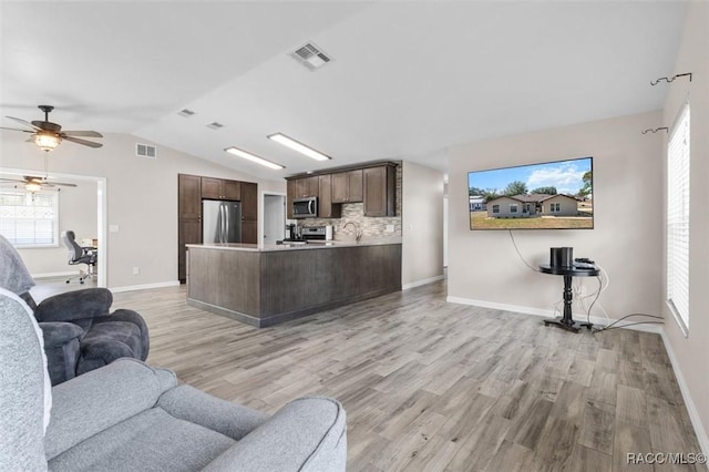 living room featuring light hardwood / wood-style flooring, vaulted ceiling, and ceiling fan