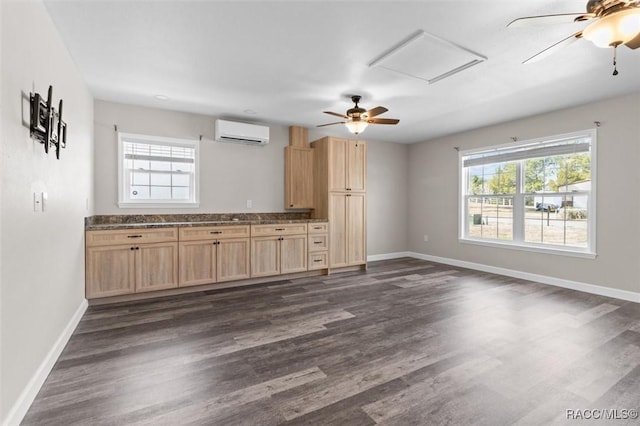 kitchen featuring light brown cabinetry, dark wood-type flooring, a wall unit AC, and ceiling fan